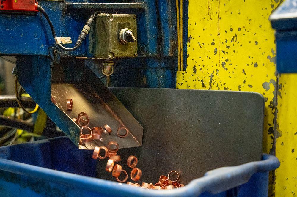 Close-up of tube cutting process producing precise PEX crimp rings with clean, burr-free edges
